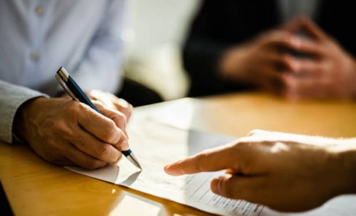 Close up of unrecognizable female person signing a contract on a meeting with agent.